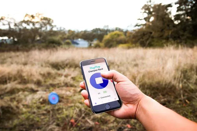 Hand holding app over a disc golf course